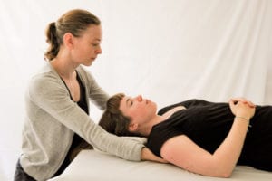 female massage therapist performing relaxing massage therapy techniques on her client